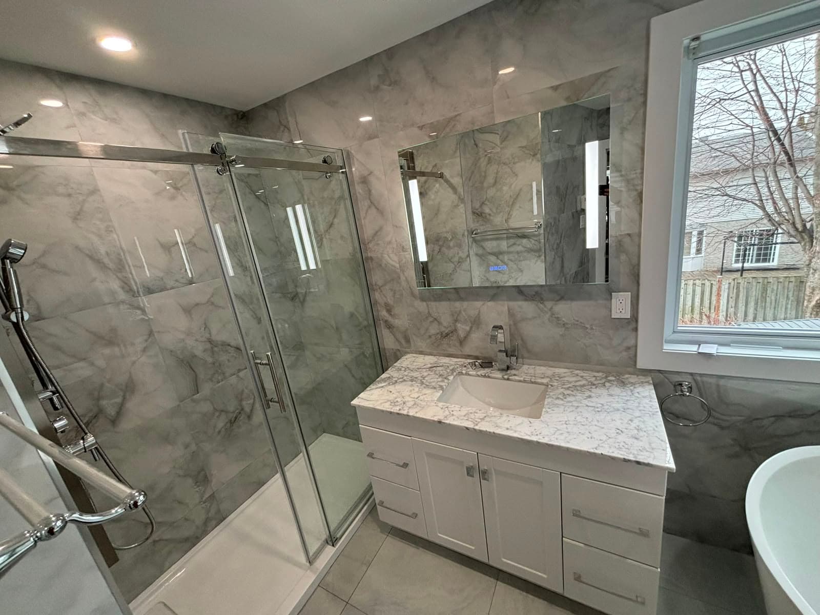 Salle de bain avec douche en verre, céramique effet marbre et vanité en pierre